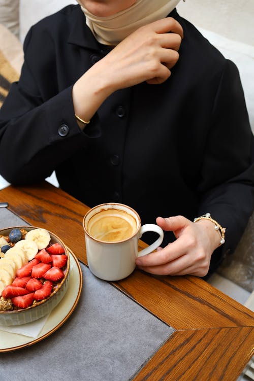 Woman Sitting at Table with Coffee in Mug