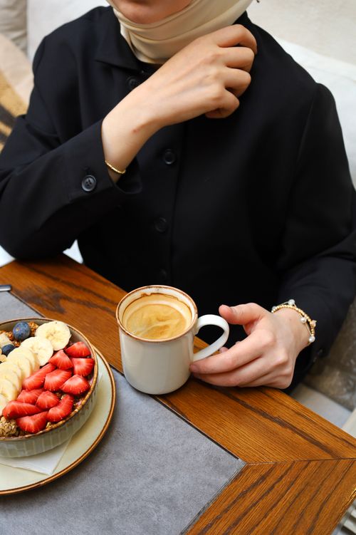 Free An elegant woman enjoys coffee and a fresh fruit bowl at a cozy café in Istanbul. Stock Photo