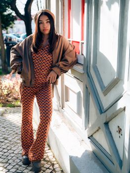 Stylish woman in chevron outfit posing on a sunny Lisbon street, showcasing urban fashion.