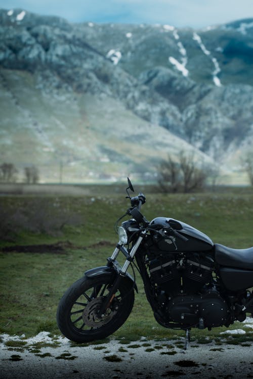 A black motorcycle parked in a field near mountains