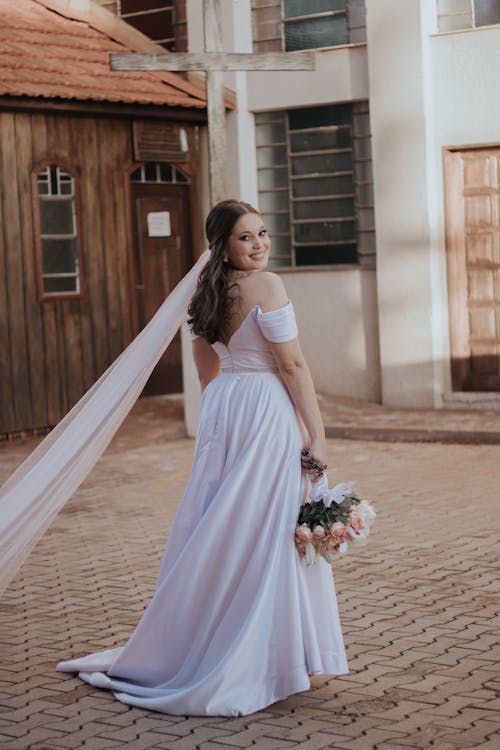 A bride in a wedding dress standing in front of a brick building