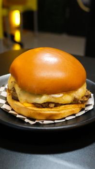 Close-up of a juicy cheeseburger with melted cheese served on a plate, perfect for fast food lovers.