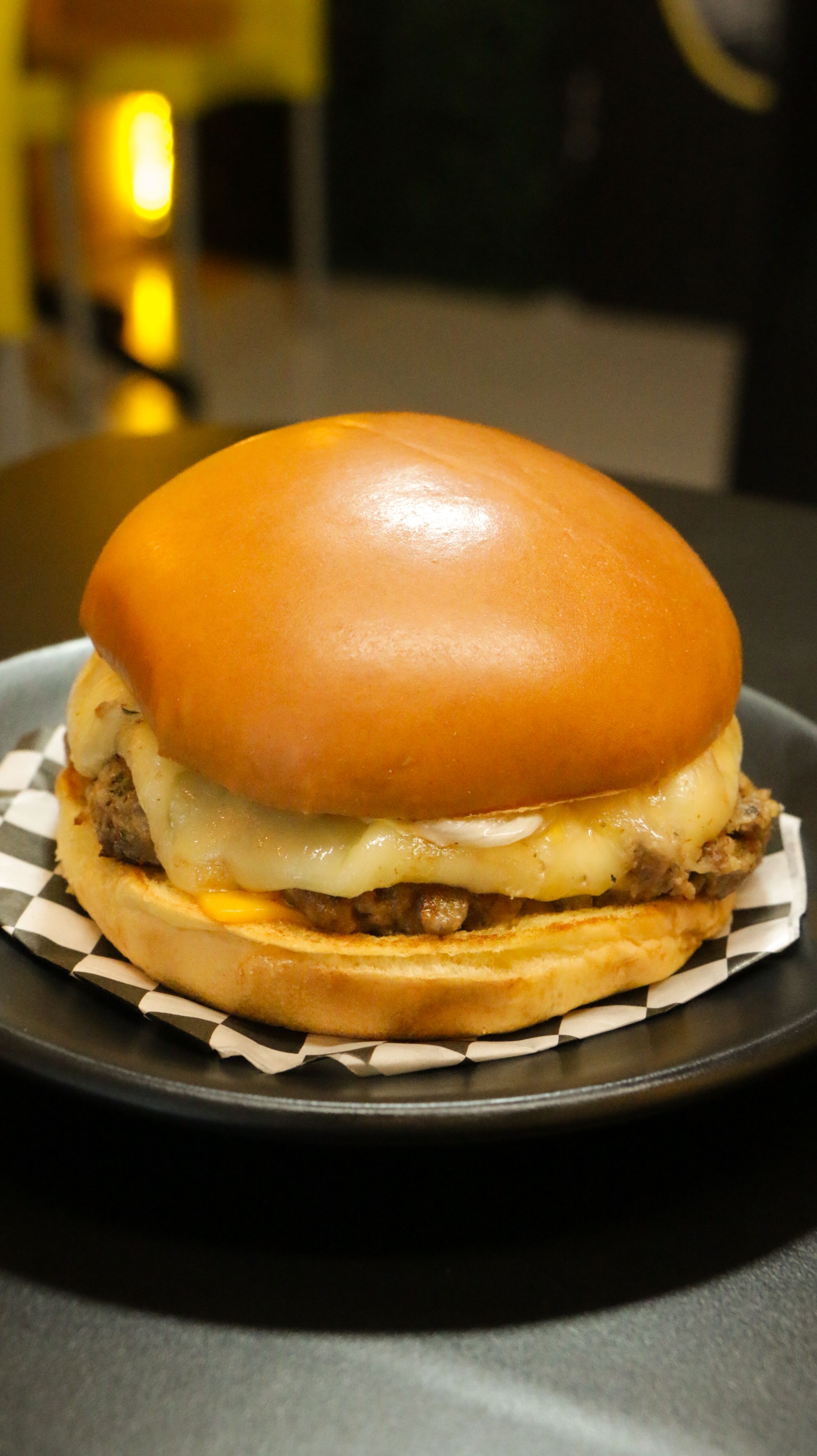 Close-up of a juicy cheeseburger with melting cheese on a plate.