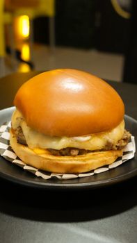 Close-up of a juicy cheeseburger with melting cheese on a plate.