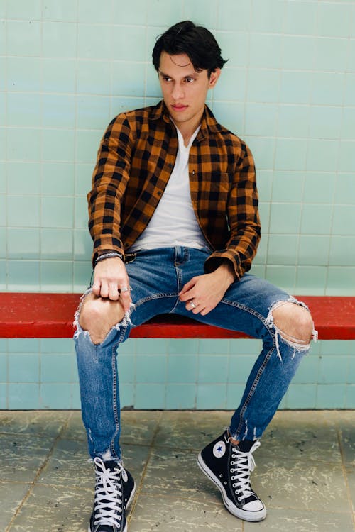 Man in Shirt and Torn Jeans Sitting on Bench
