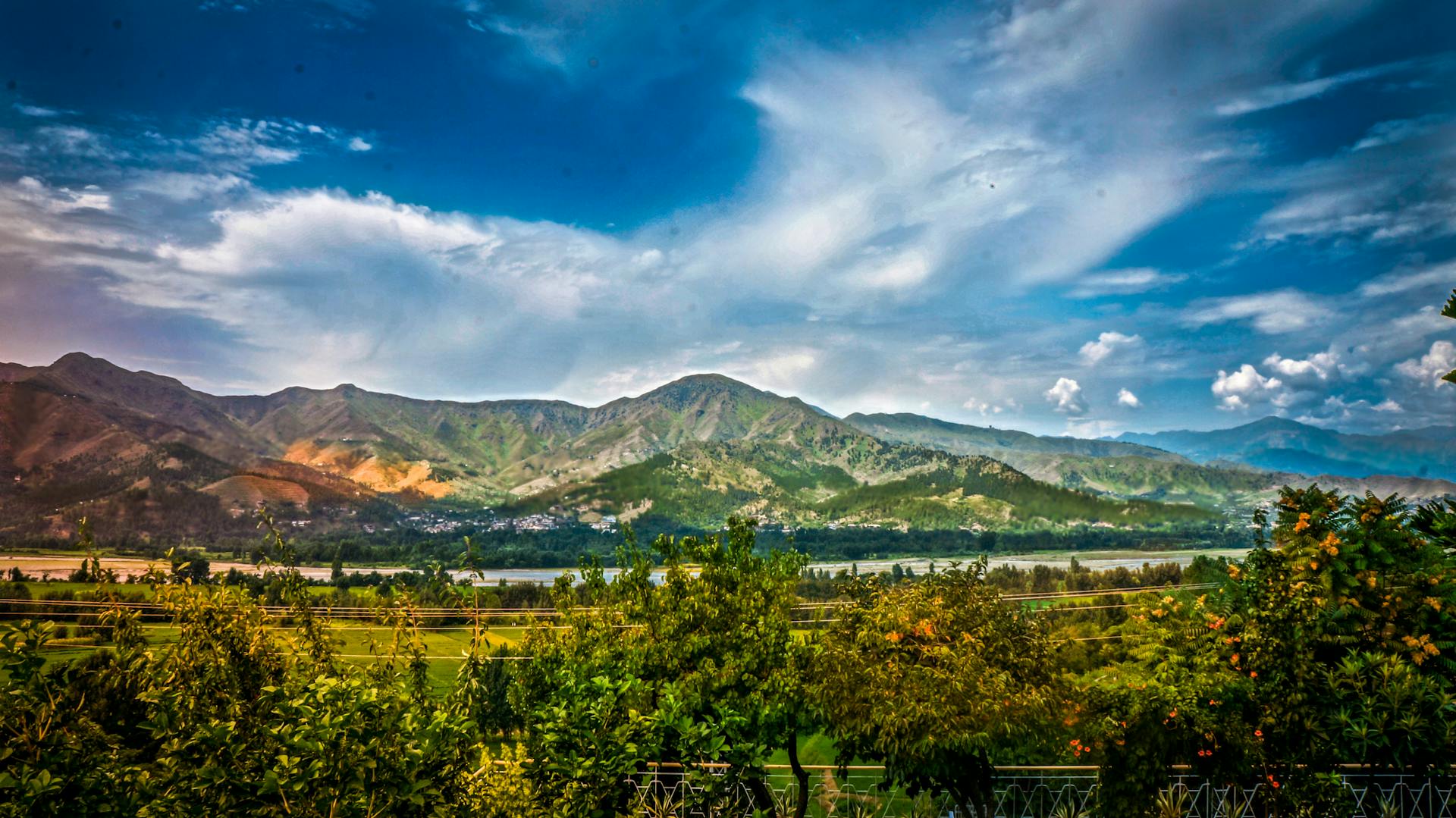 Breathtaking view of mountains and valley in Kalam, Pakistan under a vibrant sky.