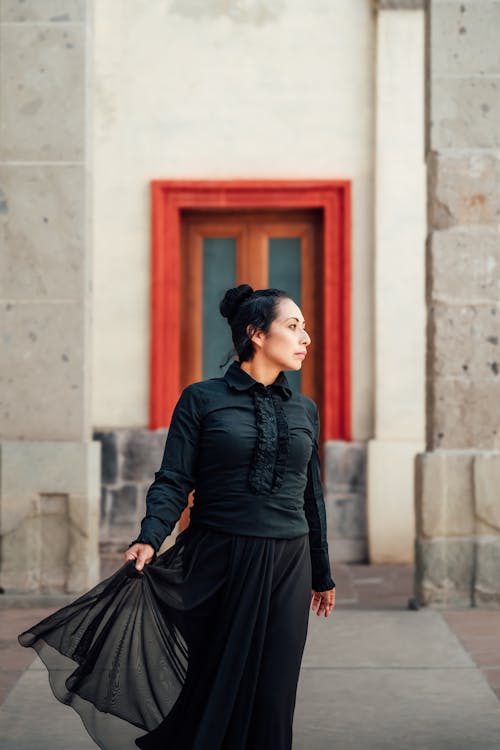A woman in a black dress is walking down the street