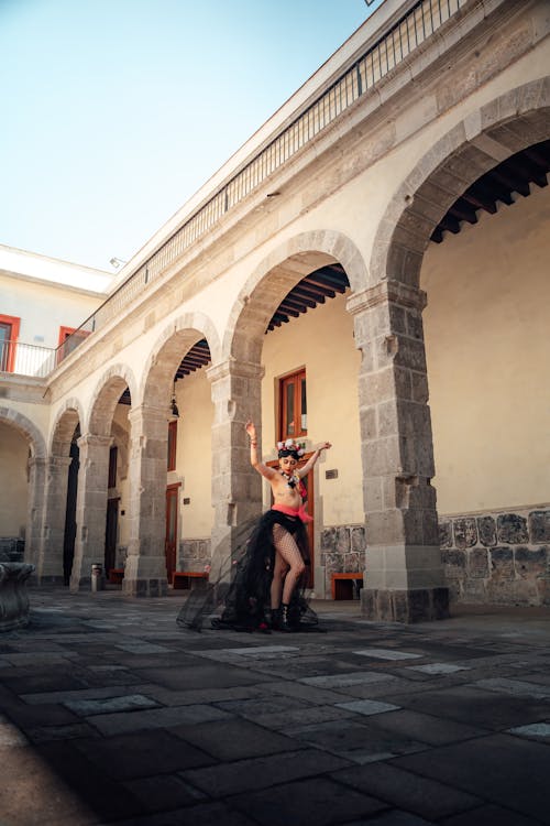 A woman in a black dress is dancing in an arched building