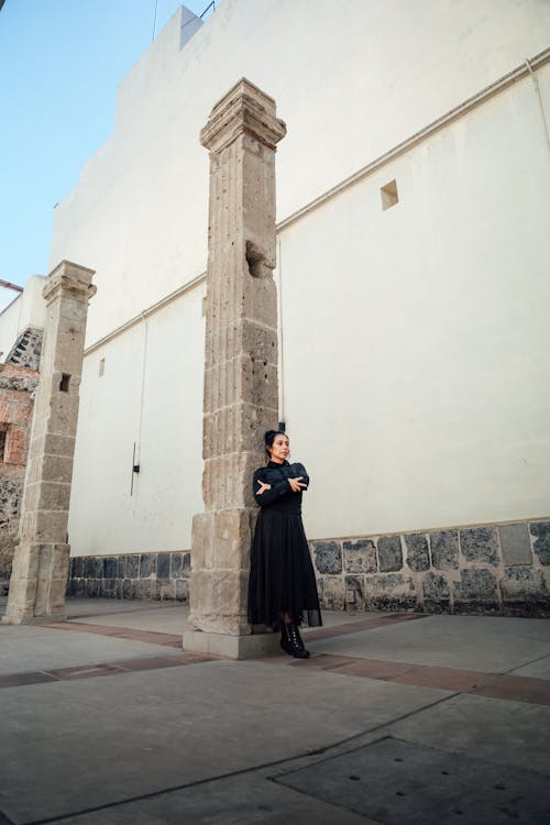 A woman in black dress standing in front of pillars
