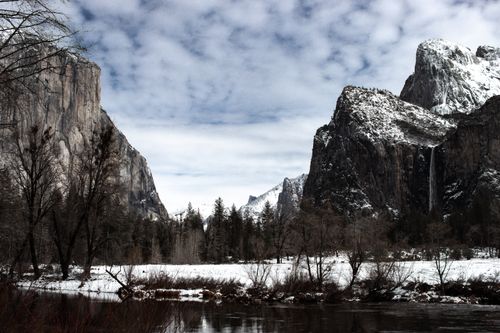 Free Snow-covered Yosemite Valley featuring El Capitan and waterfalls under cloudy skies. Stock Photo