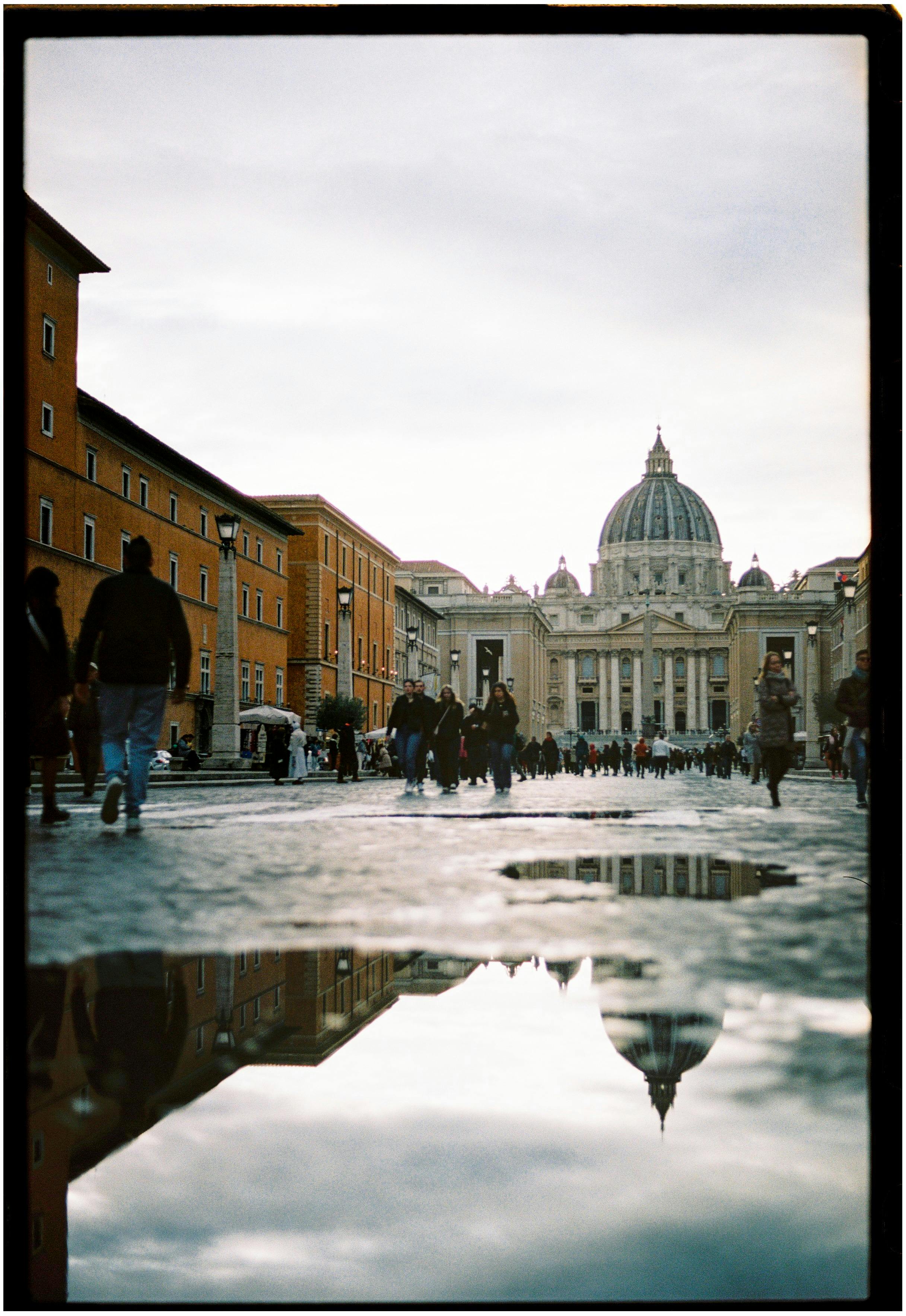 Stunning view of St. Peter's Basilica reflected in rain puddles, Vatican City.