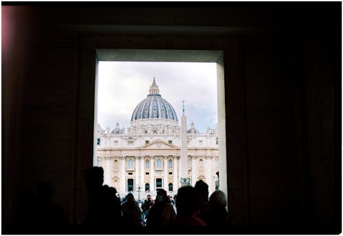 People are looking out of a window at the dome of st peter's basilica