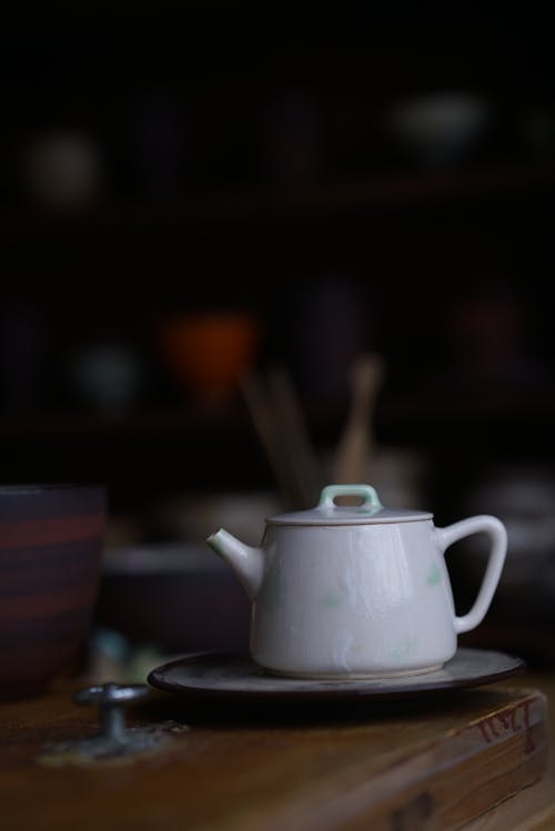 A small white teapot sits on a wooden table