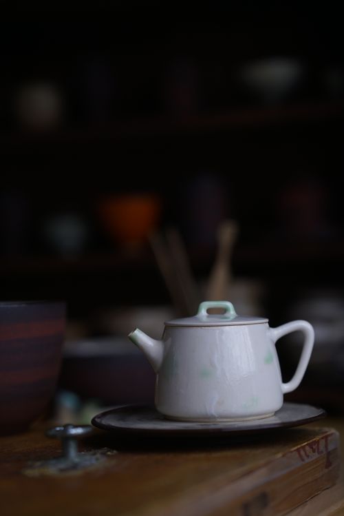 Free Elegant white ceramic teapot on a rustic wooden table, captured with soft lighting in a cozy atmosphere. Stock Photo