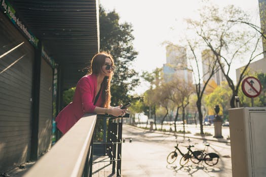 Stylish woman in a pink blazer enjoying a sunny day in Mexico City's urban landscape.
