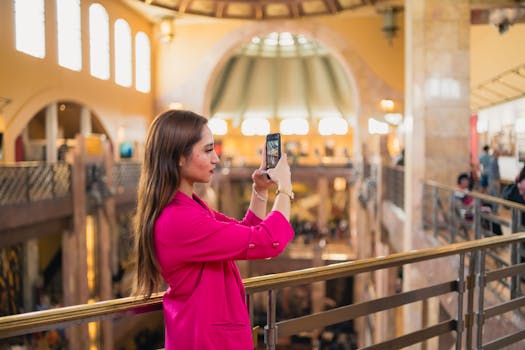 Woman in a vibrant pink outfit taking a photo inside a luxurious shopping center in Mexico City.