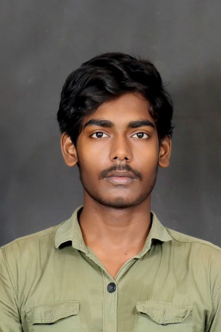 Professional studio portrait of a young man against a gray background.