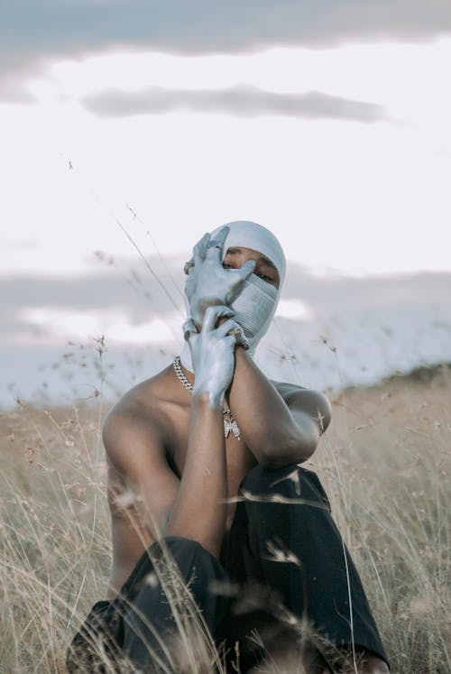 A man in a silver mask sitting in a field