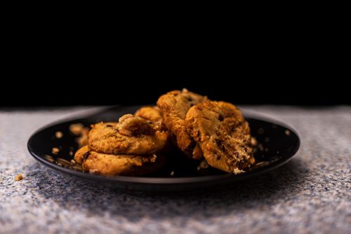 Free Freshly baked chocolate chip cookies displayed on a black plate in a cozy setting. Stock Photo