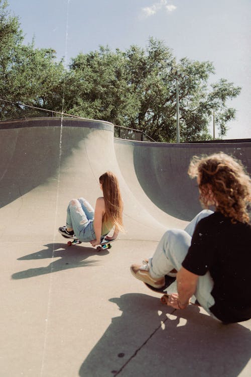 Two people sitting on the edge of a skateboard ramp