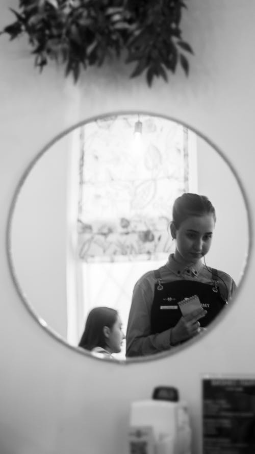 A woman is looking at her reflection in a mirror