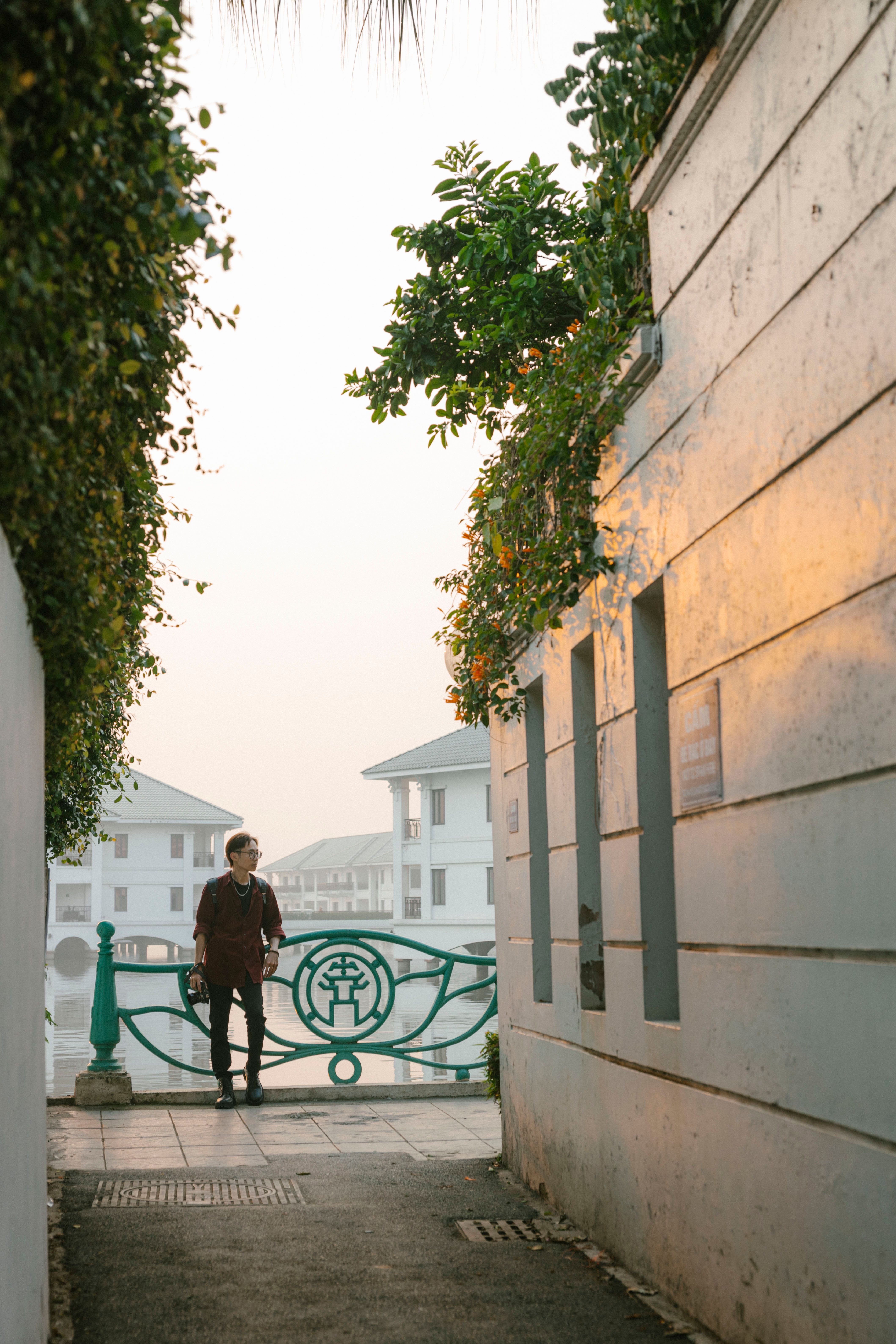 Man Standing by Railing behind Buildings Walls · Free Stock Photo