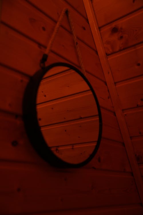A round mirror hanging on the wall of a wooden cabin