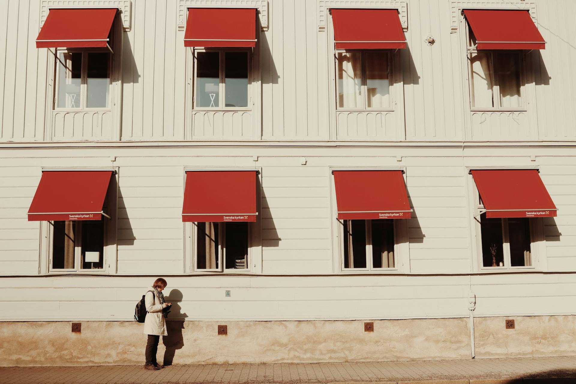 Scandinavian architecture with a person outside, red awnings in Jönköping, Sweden.