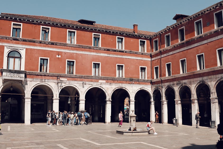Venetian courtyard in San Giacomo di Rialto with visitors. Classic architecture and urban setting.