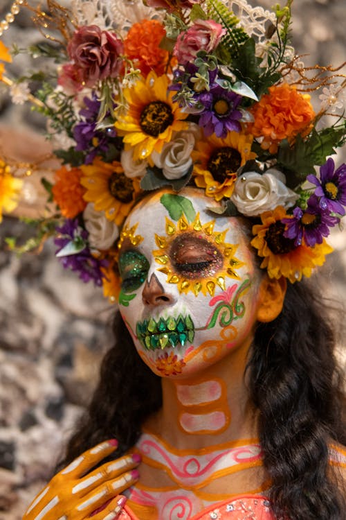 A woman with a flower painted face and flowers in her hair