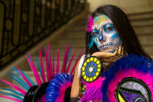 A woman with a colorful face paint and feathers