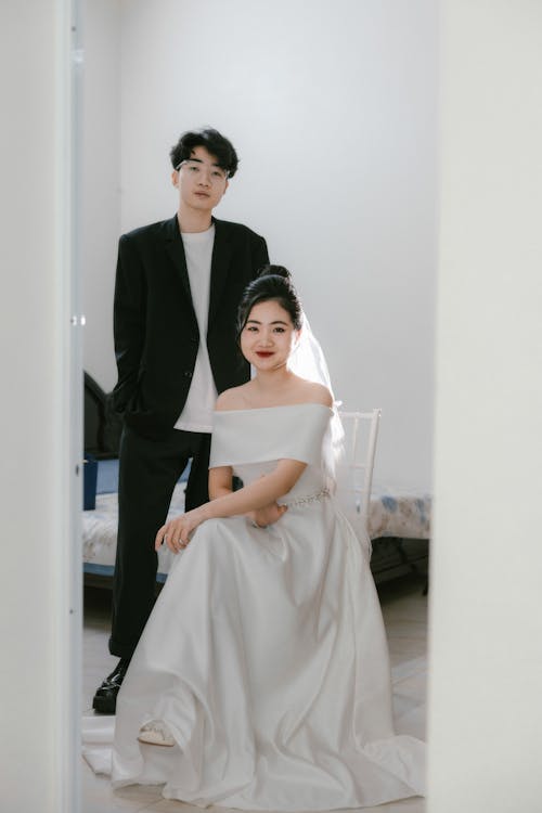 A bride and groom in formal attire pose for a photo