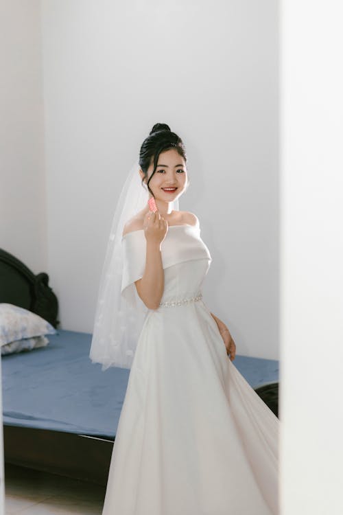 A bride in a white wedding dress is posing for a photo