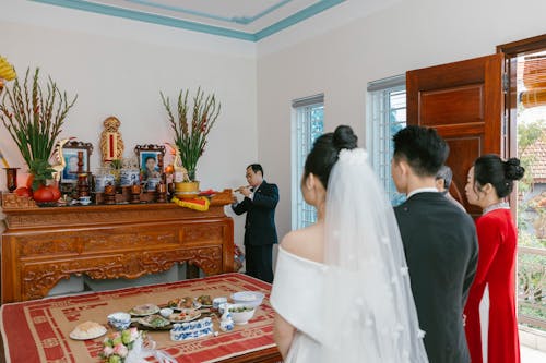 A bride and groom are standing in front of a shrine