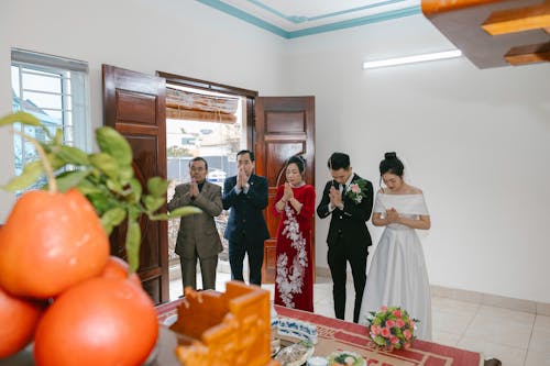 A bride and groom are standing in front of a fruit bowl
