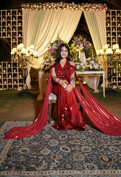 Free Woman in a red gown posing elegantly at a stylish event with luxurious decor and flowers. Stock Photo