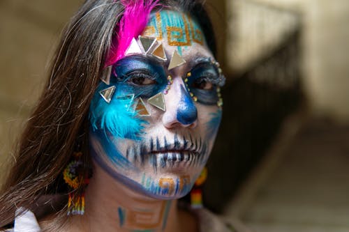 A woman with a painted face and colorful feathers