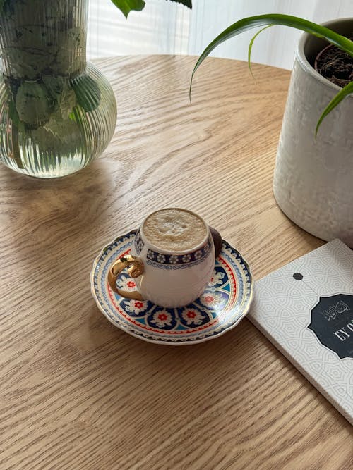 A cup of coffee on a table next to a book