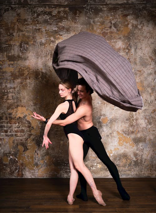 Two dancers in a studio pose with a blanket