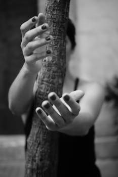 一幅黑白肖像画中，一名女子伸手抓向树干，重点突出她的双手