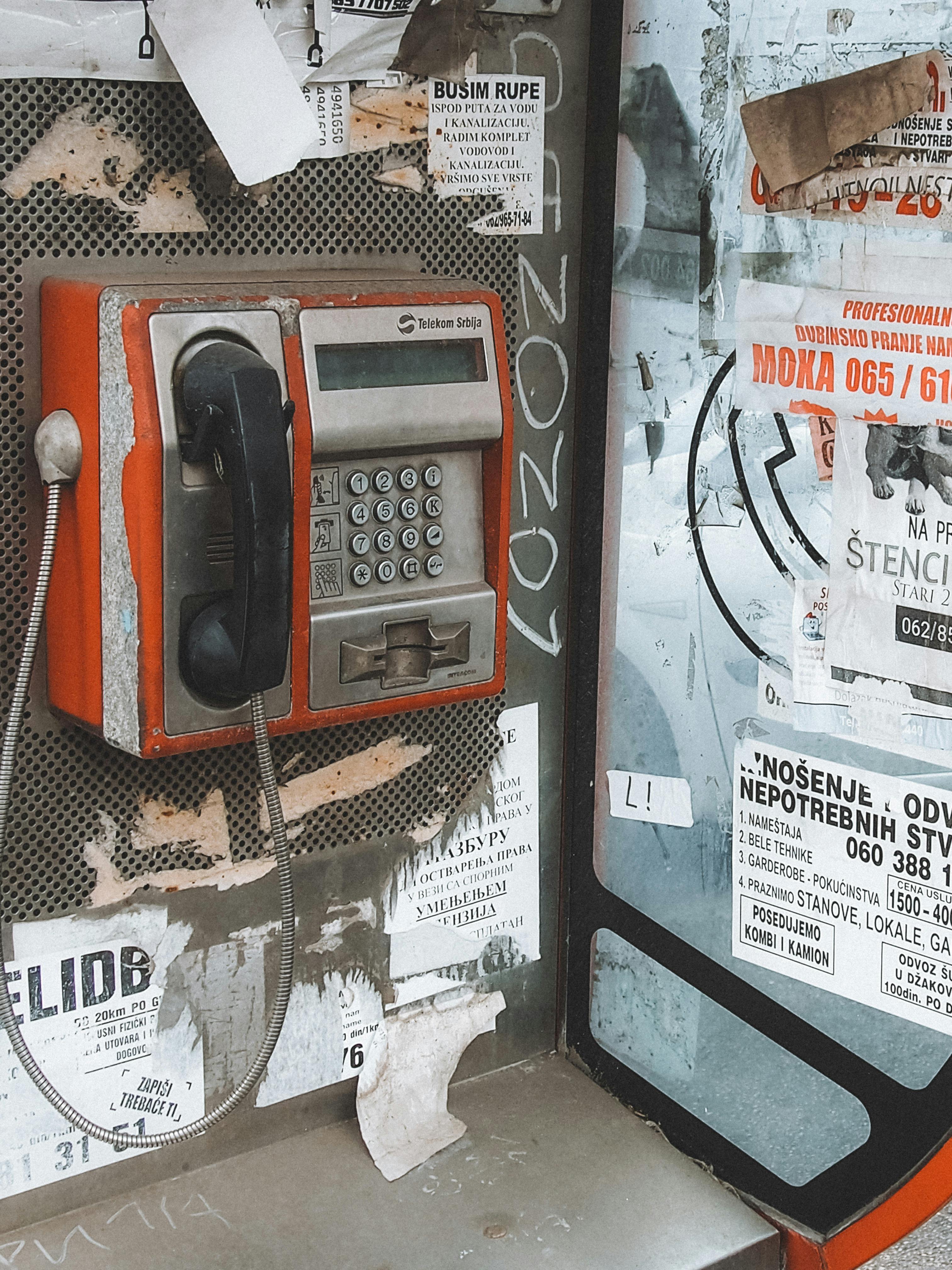 A retro red payphone surrounded by urban posters, capturing a vintage feel.
