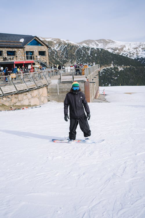 A man standing on a snowboard in front of a building