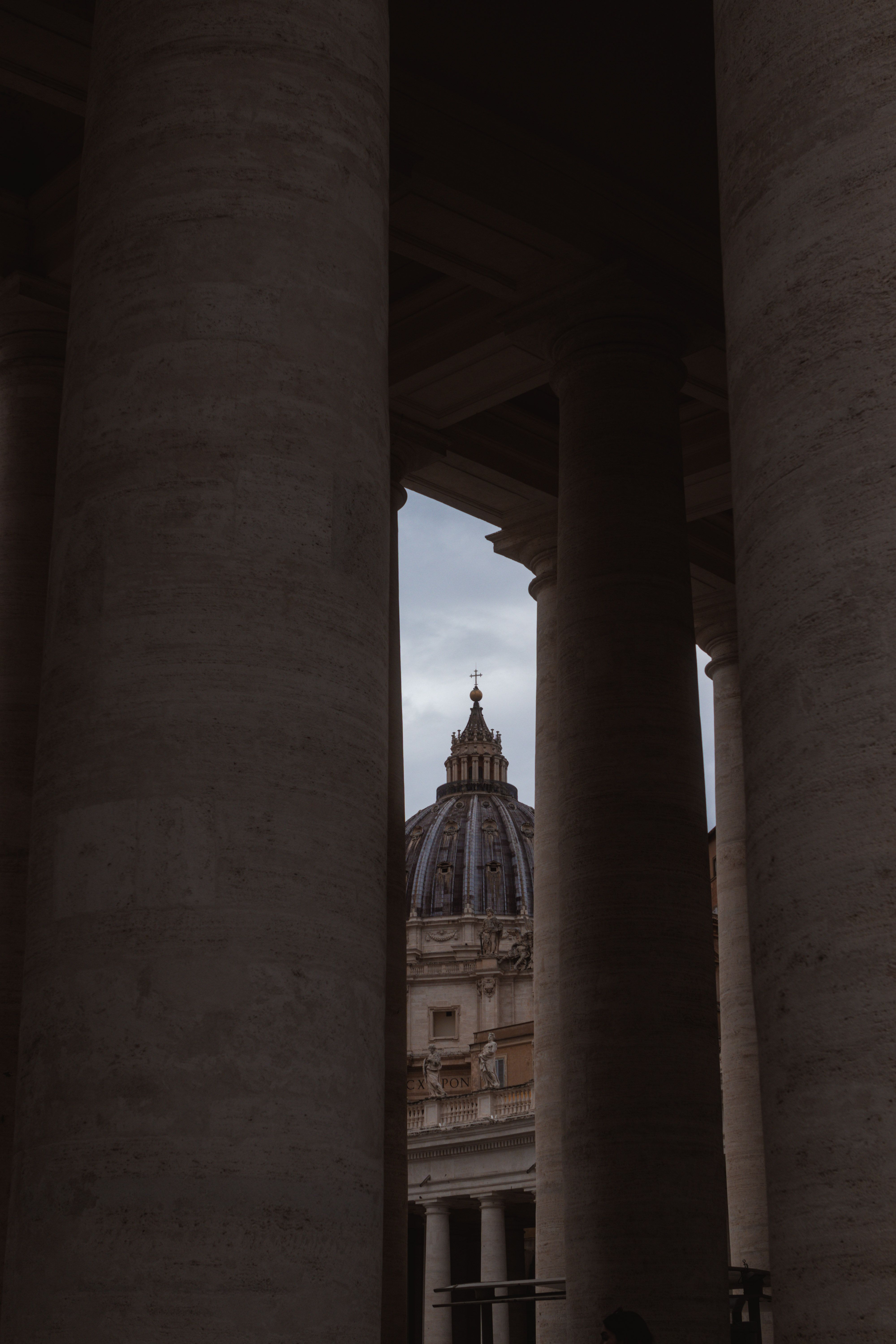 View of St. Peter's Basilica dome seen through the Vatican's massive columns.