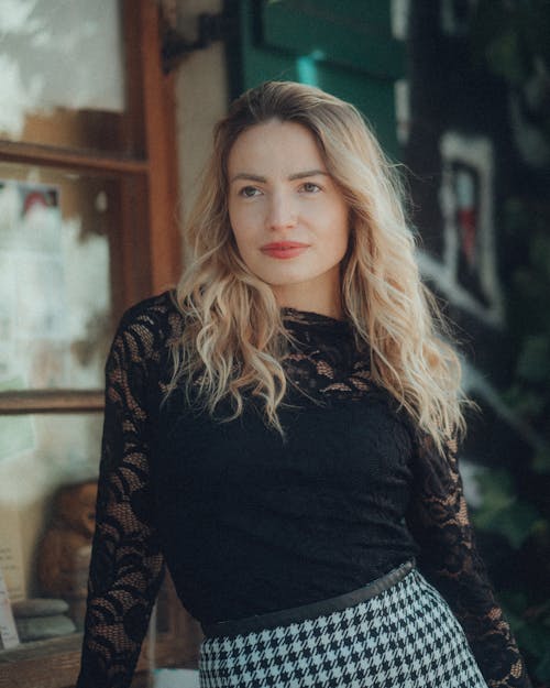 A blonde woman in a black top and plaid skirt