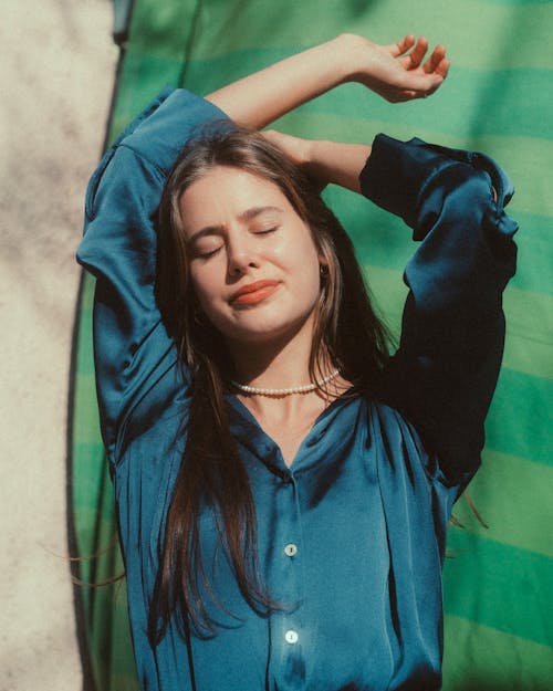 Free A woman in a blue shirt with her hands on her head Stock Photo