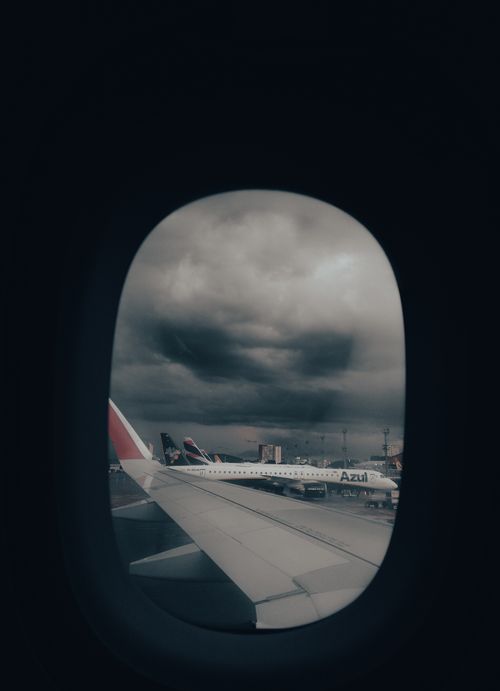 Free View from airplane window showing wing and stormy clouds at airport. Stock Photo