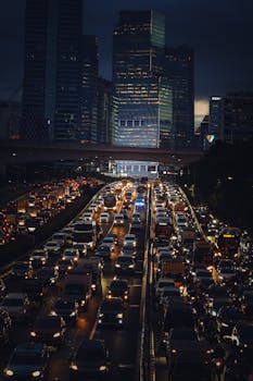 Dense nighttime traffic on Jakarta's busy highway with illuminated skyscrapers in the background.