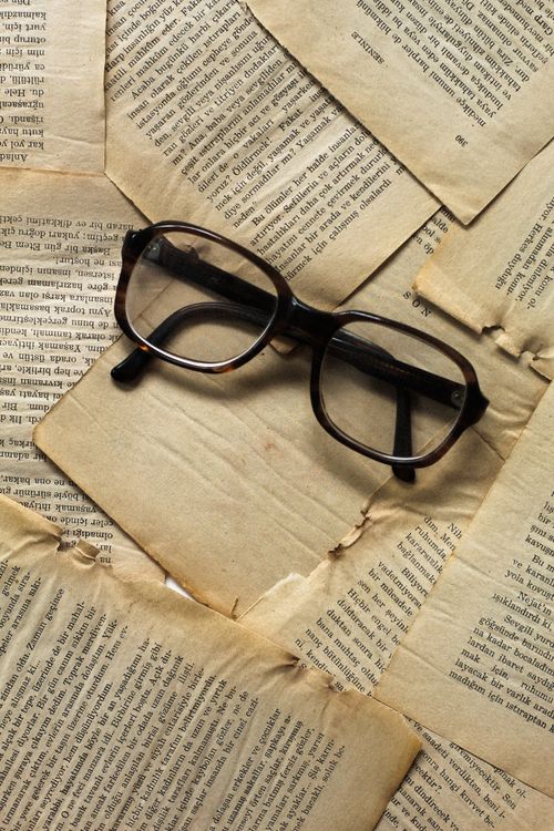Free Top view of vintage eyeglasses resting on scattered antique book pages, evoking a sense of knowledge. Stock Photo