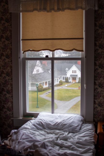 View from a cozy bedroom window overlooking charming houses and a garden.