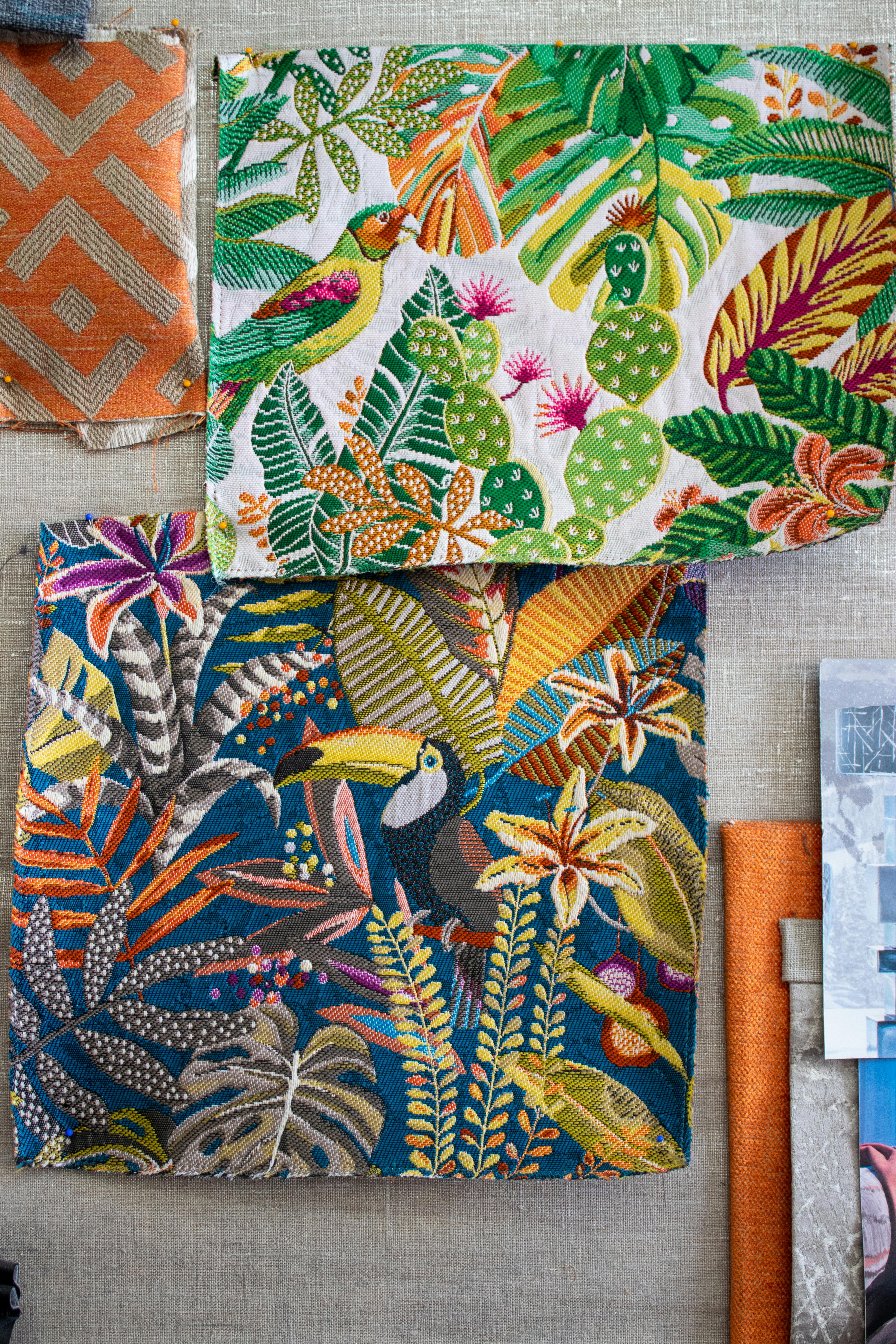 Colorful fabrics featuring tropical motifs and patterns in a flat lay composition.